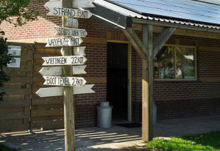 Wooden signpost with distances to local destinations at campsite de Boerenzwaluw, North Holland, Netherlands.