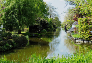Idyllisk kanal udsigt ved Safari-telt på Campingplads de Boerenzwaluw i Holland, omgivet af frodigt grønt.