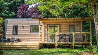 Outdoor view of COTTAGE Premium lodge with a wooden deck, garden furniture, and surrounded by trees.