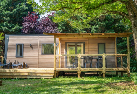 Outdoor view of COTTAGE Premium lodge with a wooden deck, garden furniture, and surrounded by trees.