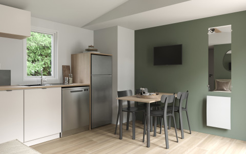 Cucina e sala da pranzo moderne nel COTTAGE Premium al Campeggio Le Château, con parete verde e TV.