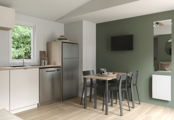 Cocina y comedor modernos en COTTAGE Premium del Camping Le Château, con pared verde y televisor.