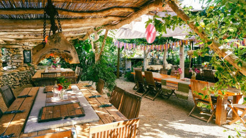 Zona pranzo all'aperto al Campeggio Les 3 Cantons in Occitania, Francia, con tavoli rustici e decorazioni colorate.