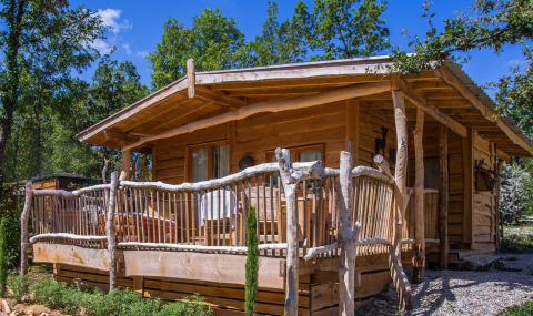 Casetta di legno al Campeggio Les 3 Cantons, Occitania, Francia, circondata da alberi verdi.