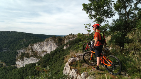 Ciclista con mountain bike sull’orlo di una scogliera al campeggio Les 3 Cantons in Occitania, Francia.