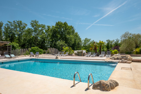 Outdoor swimming pool with sun loungers and trees at Campsite Les 3 Cantons in Occitanie, France, on a sunny day.