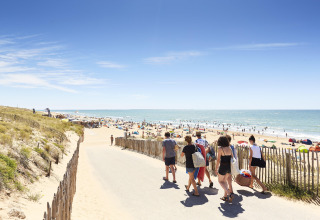 Mensen lopen naar het drukke strand bij Flower Camping l'Escale du Perthuis in Pays de la Loire, Frankrijk.