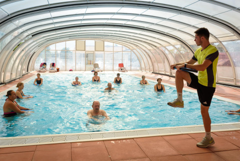 Instructor dirige clase de aquagym para adultos en piscina cubierta de Flower Camping l'Escale du Perthuis.