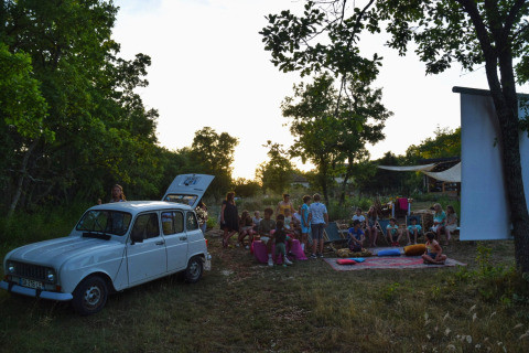 Serata cinema all'aperto con bambini e adulti al campeggio Les 3 Cantons in Occitania, Francia.