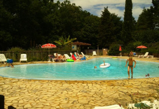 Piscina all'aperto del campeggio La Grande Véyière in Nouvelle-Aquitaine, Francia, con ospiti che nuotano.