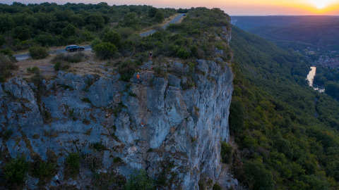 Sunset above a steep cliff with climbers near St Antonin Noble Val in Occitanie, France.