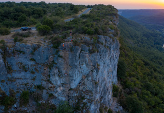 Tramonto su una ripida scogliera con arrampicatori vicino a St Antonin Noble Val, Occitania, Francia.