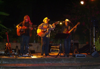 Band dal vivo si esibisce di notte sul palco al campeggio La Grande Véyière, parco vacanze in Nouvelle-Aquitaine, Francia.