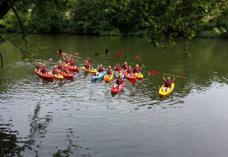 A group kayaking on a scenic river near St Antonin Noble Val, Occitanie, France, surrounded by lush greenery.