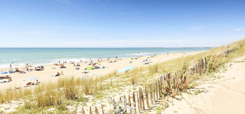 Strand bij La Tranche-sur-Mer in Pays de la Loire, Frankrijk, met duinen, strandgangers en parasols.