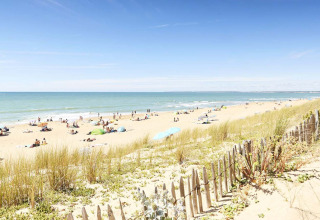 Strand bij La Tranche-sur-Mer in Pays de la Loire, Frankrijk, met duinen, strandgangers en parasols.