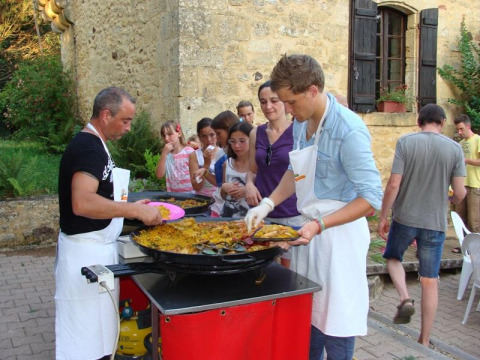 Persone in fila per il cibo servito da una grande padella al campeggio La Grande Véyière in Francia.