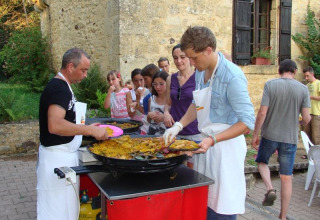 Persone in fila per il cibo servito da una grande padella al campeggio La Grande Véyière in Francia.