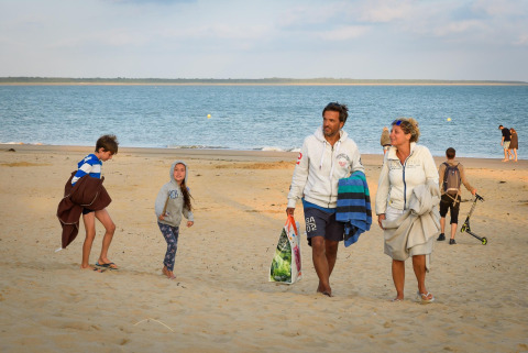 Family walking on the sandy beach at Flower Camping l'Escale du Perthuis, Pays de la Loire, France.