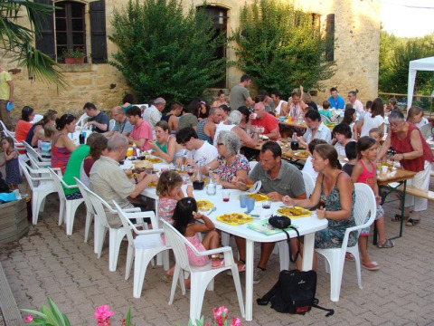 Persone che condividono un pasto all'aperto presso i tavoli del campeggio La Grande Véyière in Francia.