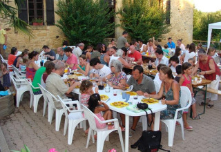 Persone che condividono un pasto all'aperto presso i tavoli del campeggio La Grande Véyière in Francia.