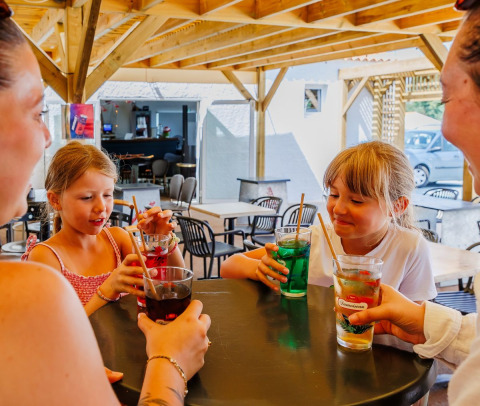 Famiglia beve bibite colorate a un tavolo al Flower Camping l'Escale du Perthuis, Pays de la Loire, Francia.