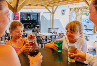 Family enjoys colorful drinks together at a table at Flower Camping l'Escale du Perthuis in Pays de la Loire, France.