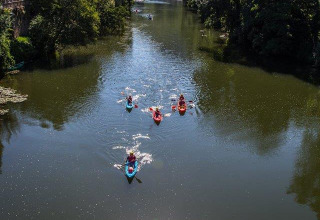 People kayak down a scenic river with forested banks at Campsite «Les 3 Cantons» in Occitanie, France.