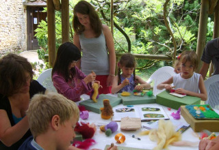 Bambini e adulti partecipano a un’attività artistica all’aperto al campeggio La Grande Véyière in Francia.