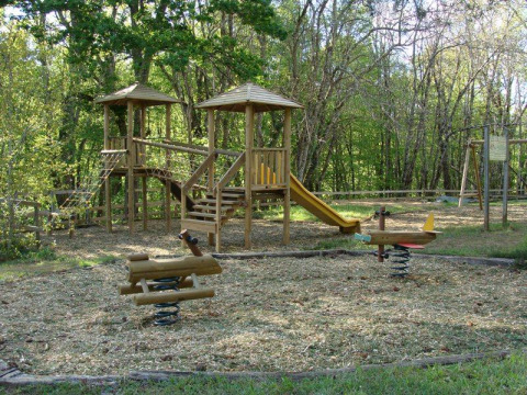 Parco giochi in legno con scivolo e giochi a molla in un campeggio di Nouvelle-Aquitaine, Francia.