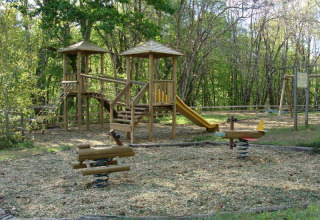 Parco giochi in legno con scivolo e giochi a molla in un campeggio di Nouvelle-Aquitaine, Francia.