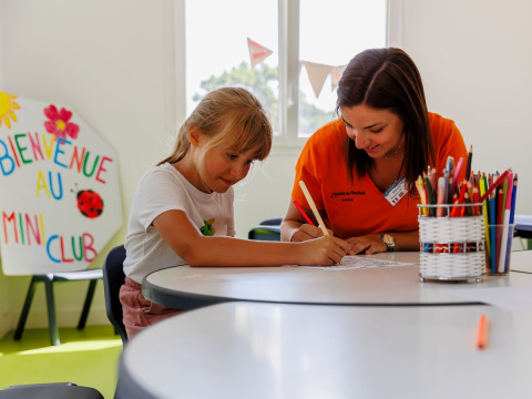 Girl and adult coloring together at a table in the kids’ club at Flower Camping l'Escale du Perthuis, France.
