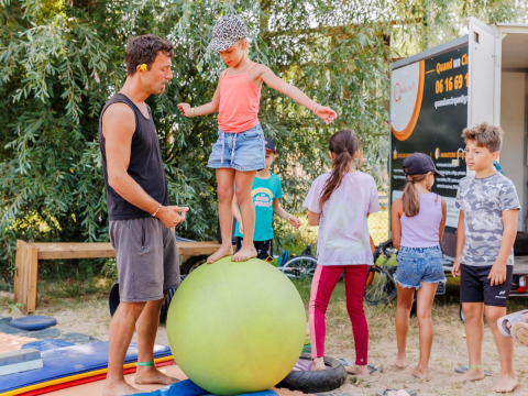 Kinderen balanceren op een grote bal met een volwassene bij Flower Camping l'Escale du Perthuis in Pays de la Loire.