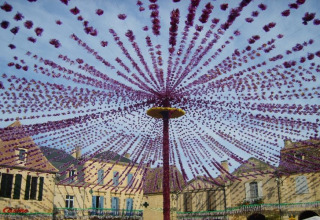 Festone viola decorano una piazza circondata da case di pietra a Molières, Nouvelle-Aquitaine, Francia.