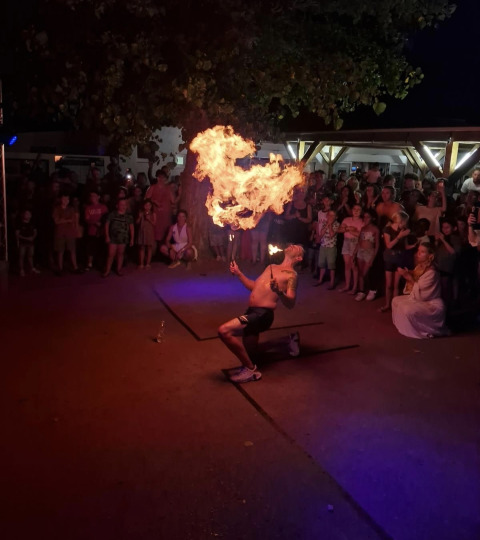 Un artista de fuego actúa ante una multitud en Flower Camping l'Escale du Perthuis, Pays de la Loire, Francia.