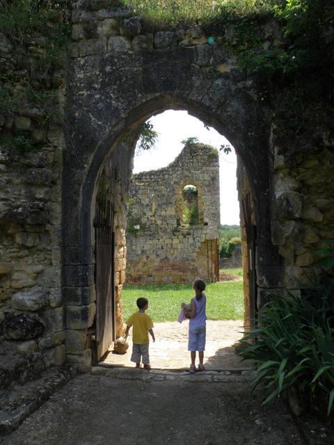 Due bambini camminano attraverso un antico arco di pietra vicino alle rovine di Molières, Nouvelle-Aquitaine, Francia.