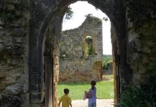 Due bambini camminano attraverso un antico arco di pietra vicino alle rovine di Molières, Nouvelle-Aquitaine, Francia.