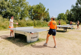 Due persone giocano a ping pong all'aperto presso il Flower Camping l'Escale du Perthuis in Pays de la Loire, Francia.