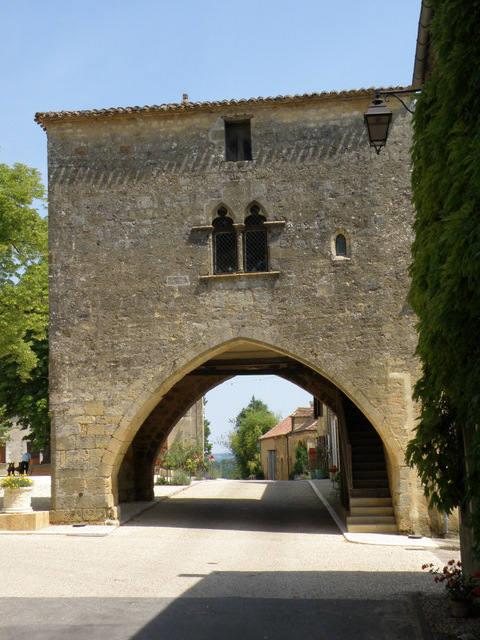 Edificio storico in pietra con arco su una strada di villaggio vicino al campeggio La Grande Véyière, Francia.