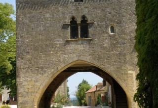 Edificio storico in pietra con arco su una strada di villaggio vicino al campeggio La Grande Véyière, Francia.