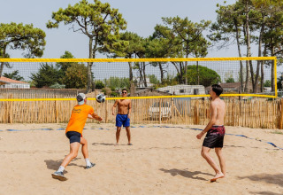Drei Männer spielen Beachvolleyball auf einem Sandplatz im Flower Camping l'Escale du Perthuis, Pays de la Loire, Frankreich.