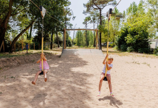 Due bambini giocano su una teleferica in un parco giochi sabbioso a Flower Camping l'Escale du Perthuis, Francia.