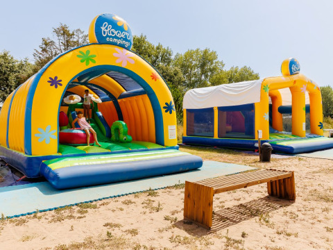 Two colorful bouncy castles and a wooden bench at Flower Camping l'Escale du Perthuis in Pays de la Loire, France.