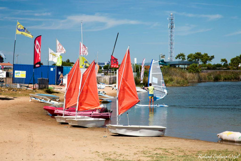 Boote mit orangefarbenen Segeln am Strand von Flower Camping l'Escale du Perthuis, Pays de la Loire, Frankreich.