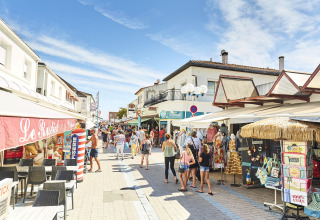 Strada pedonale affollata di negozi e bancarelle presso Flower Camping l'Escale du Perthuis, Pays de la Loire.