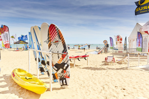 Windsurfboards, Kajak und bunte Fahnen am Sandstrand bei La Tranche-sur-Mer, Pays de la Loire, Frankreich.
