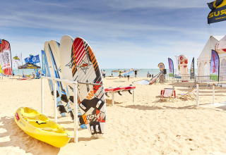 Windsurfingbrætter, kajak og farverige flag på sandstrand nær La Tranche-sur-Mer, Pays de la Loire, Frankrig.