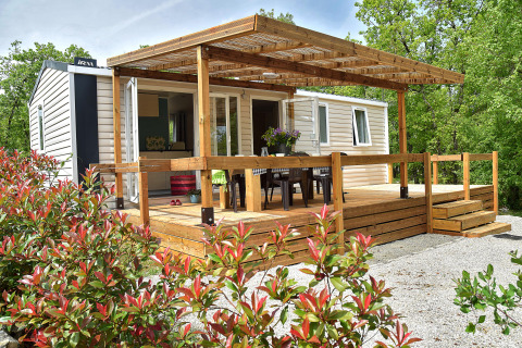 Starcaravan Lavaurette lodge featuring a wooden deck, outdoor seating, and surrounded by greenery.