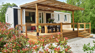 Starcaravan Lavaurette lodge featuring a wooden deck, outdoor seating, and surrounded by greenery.