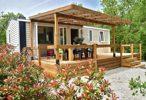 Lodge Starcaravan Lavaurette avec terrasse en bois, salon de jardin et verdure environnante.